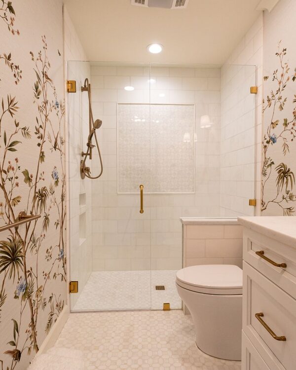Powder room with a delicate chinoiserie floral wallpaper and a round brass mirror