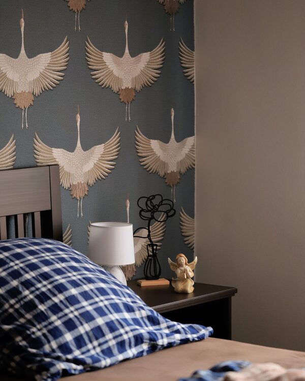 Bedroom accent wall in a soft blue crane-motif wallpaper