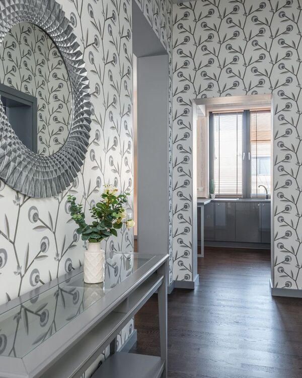 Entry hallway lined with a botanical vine wallpaper and a round mirror over a console