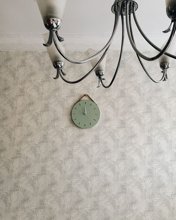 Interior with a pale fan-pattern wallpaper, a wall clock and a chandelier
