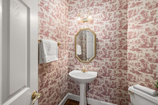 Vintage powder room in a classic red toile wallpaper with an octagonal mirror